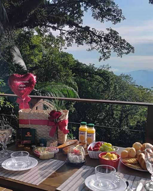 Café da manhã servido no deck, com a mata e as montanhas ao fundo